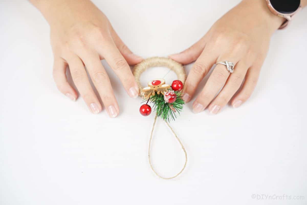 hands holding mini wreath on white table