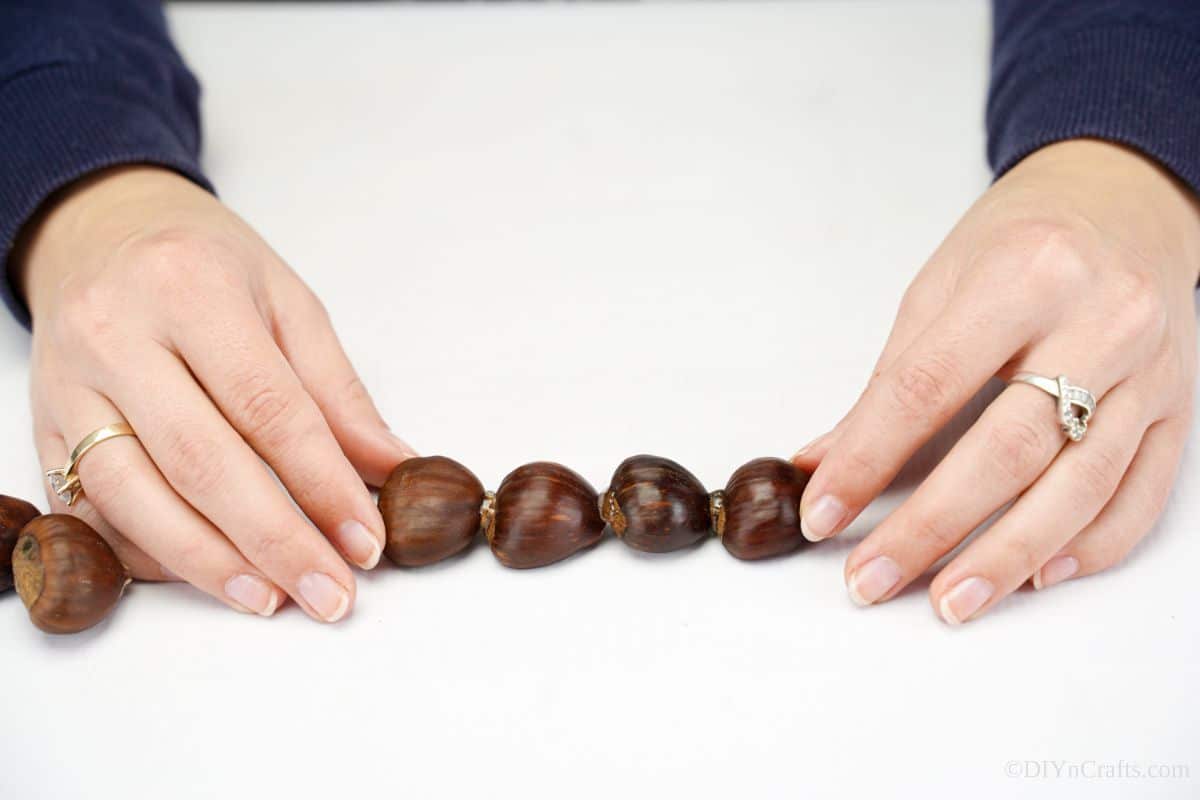 hands holding four chestnuts together while glue dries
