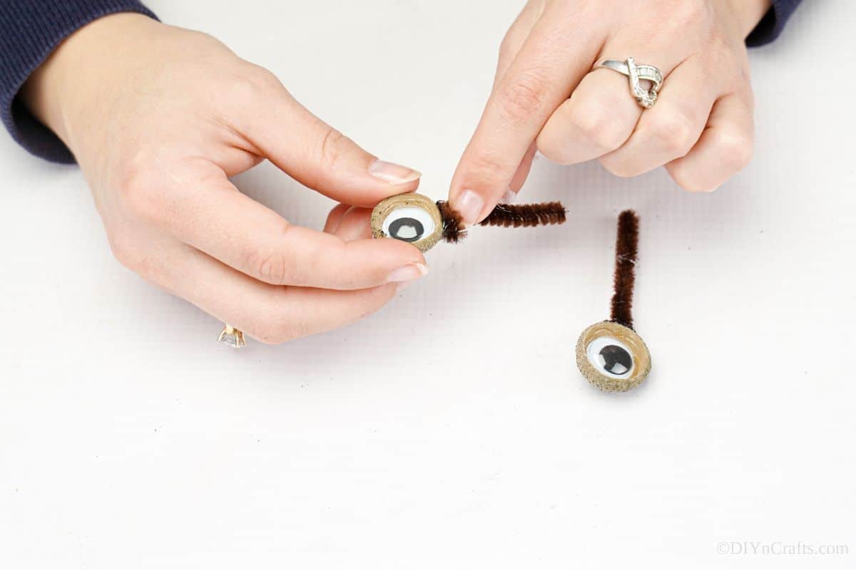 hand holding pipe cleaner to acorn top eye