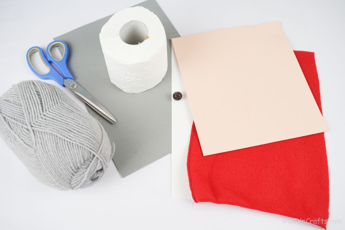 zvitek toaletnega papirja iz sive preje iz rdečega filca in sivega penastega papirja na beli mizi