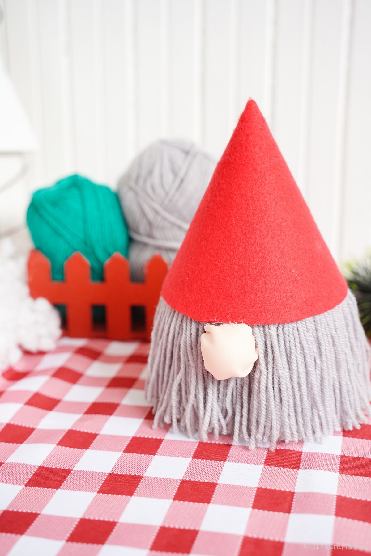 gnome with red hat and gray beard on table with red checked tablecloth