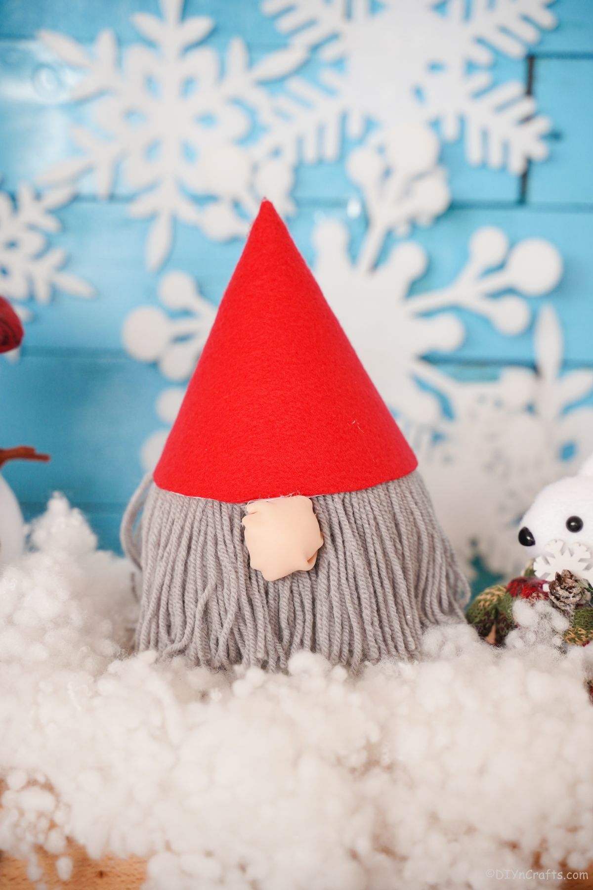 fake snow on table with blue background holding red hat gnome