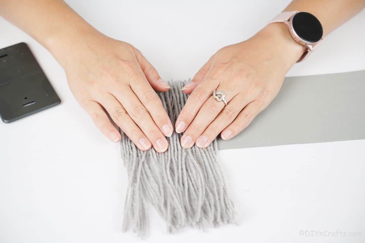 hand holding yarn down on gray paper