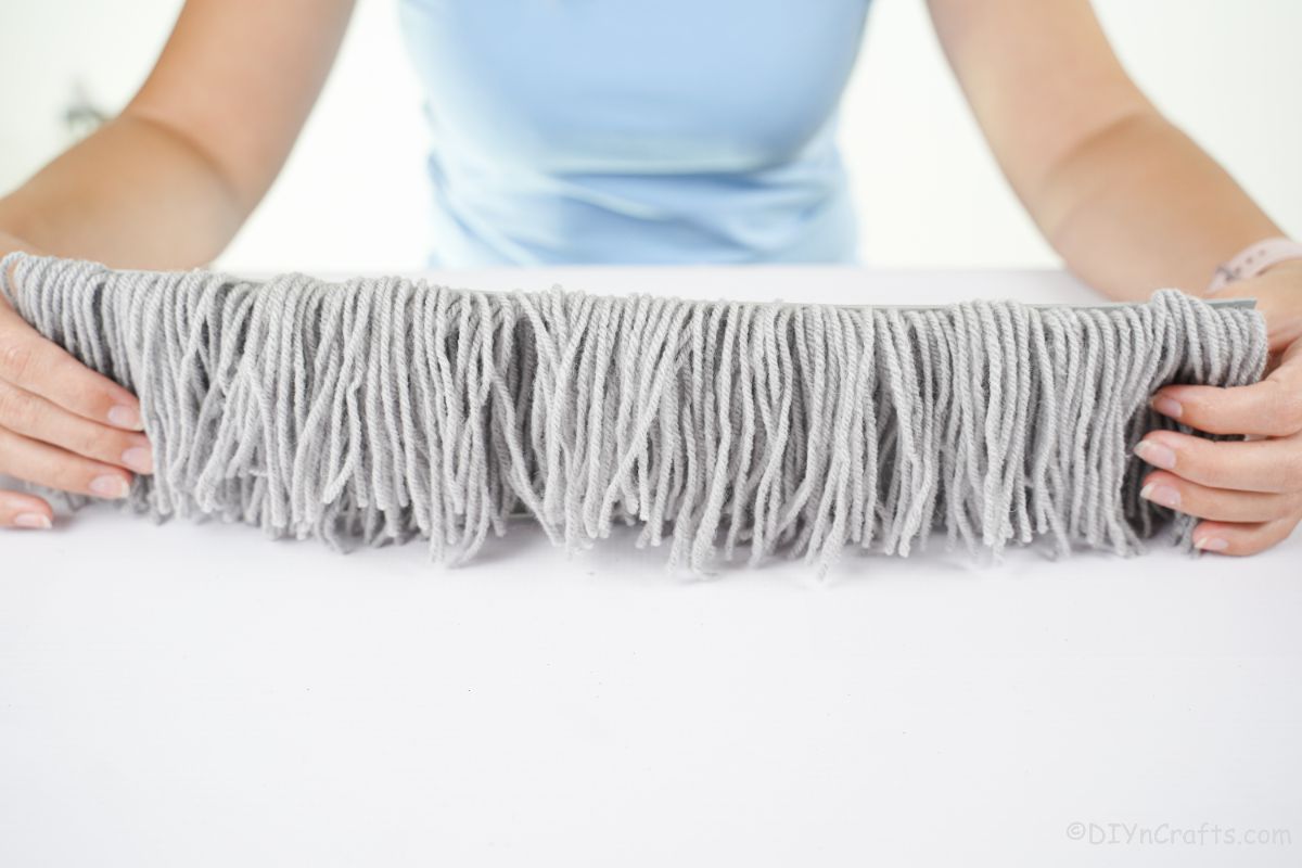 lady holding gray yarn piece on white table