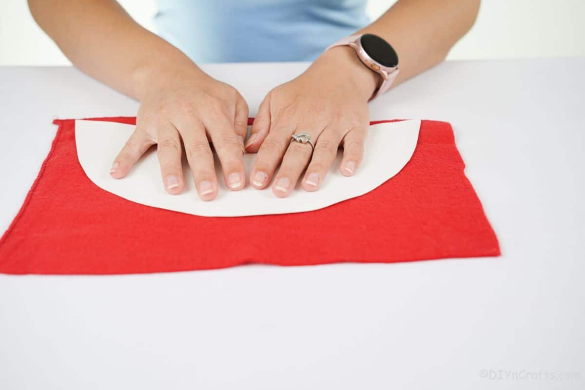 hands holding white paper on top of red felt