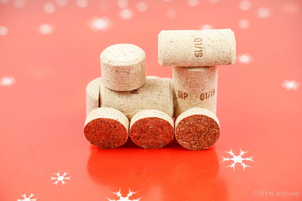 wine cork train sitting on red paper with white snowflakes