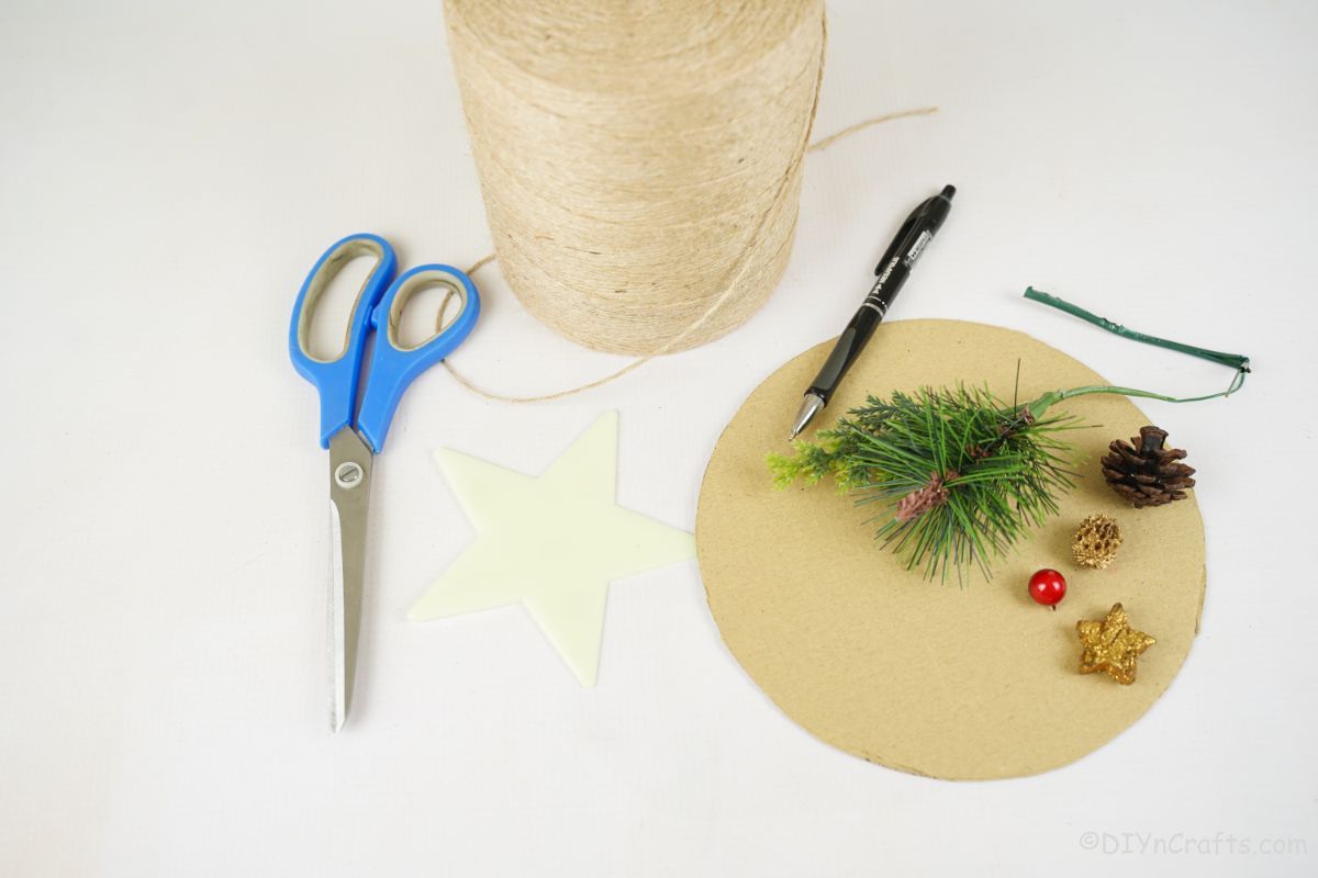 cardboard twine and greenery on white table by blue scissors