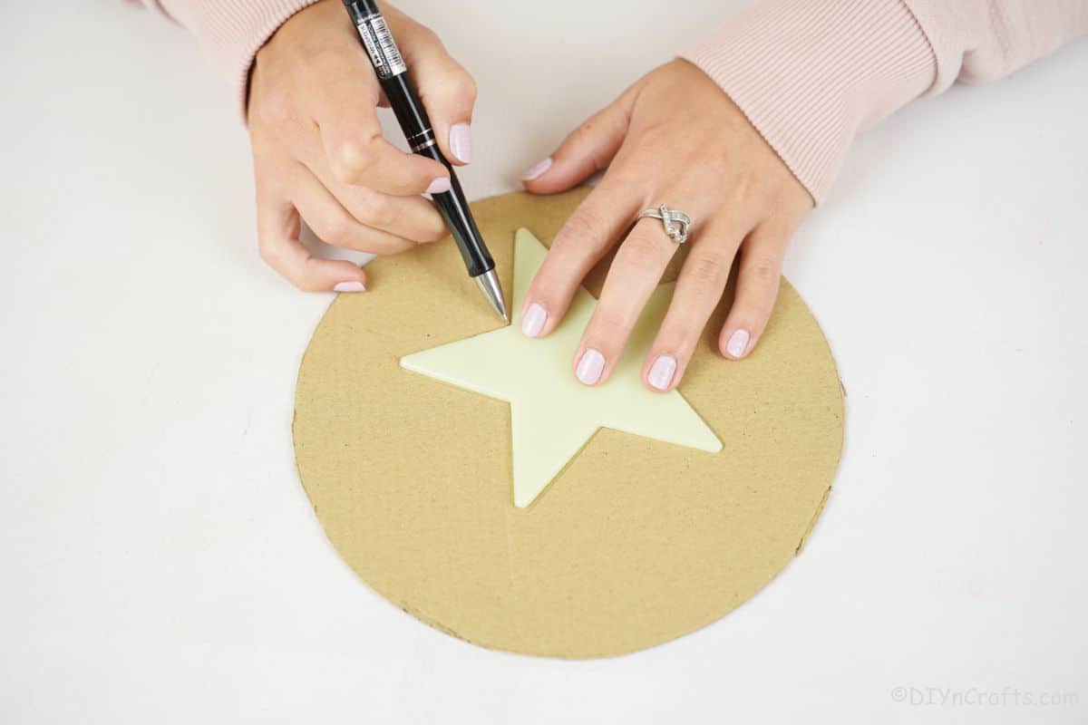hand tracing star shape on cardboard