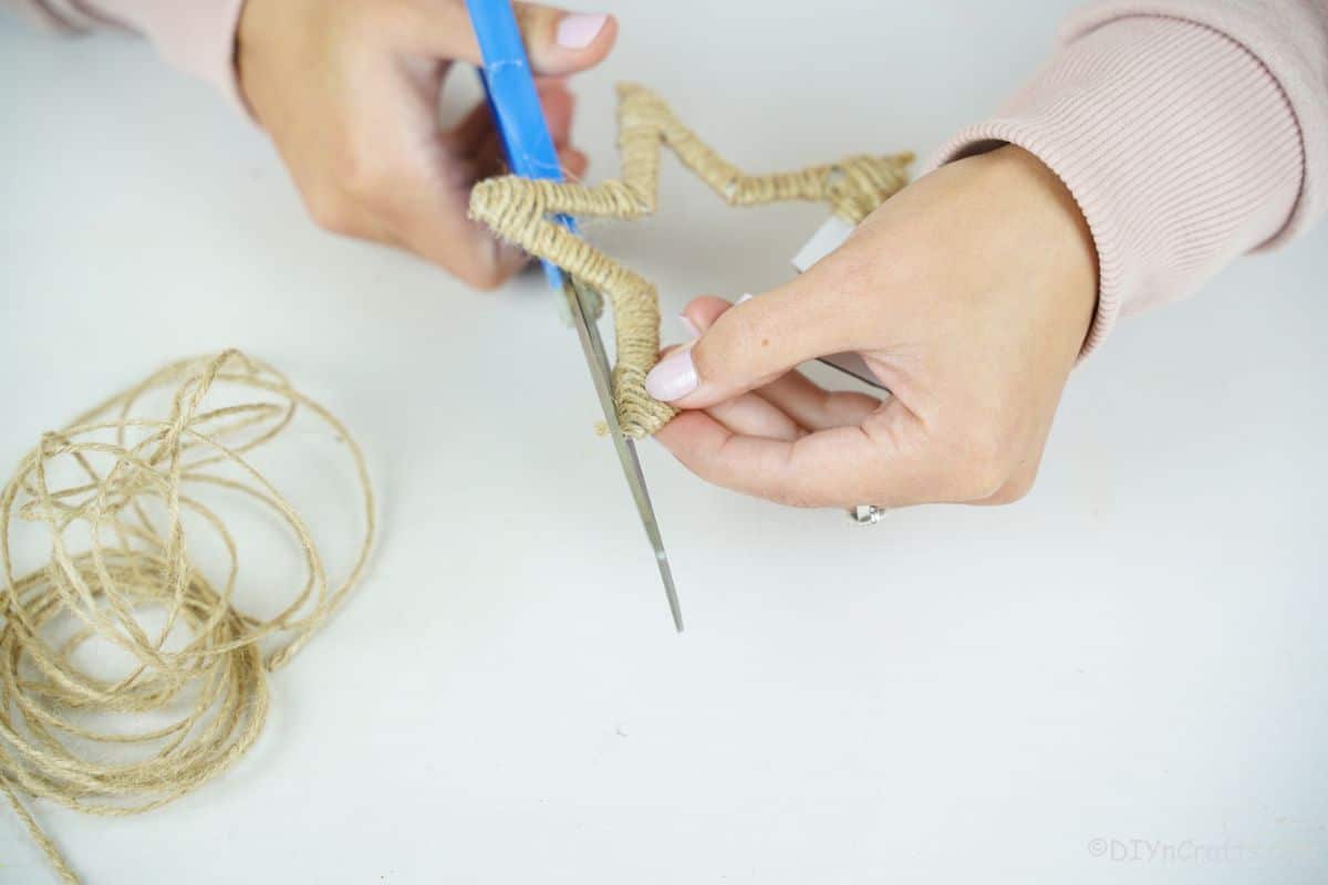 blue scissors trimming the end of twine off star