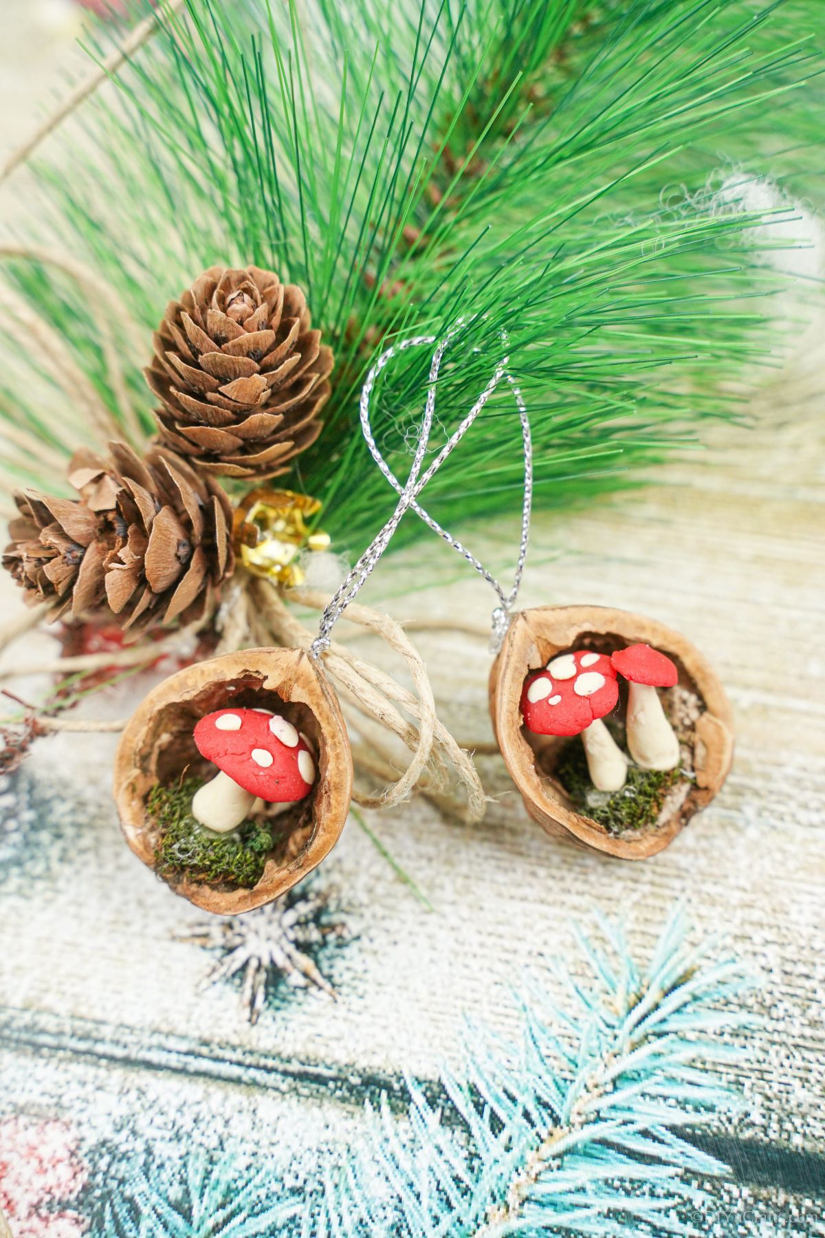 pinecones and greenery on holiday paper next to two walnut shell ornaments
