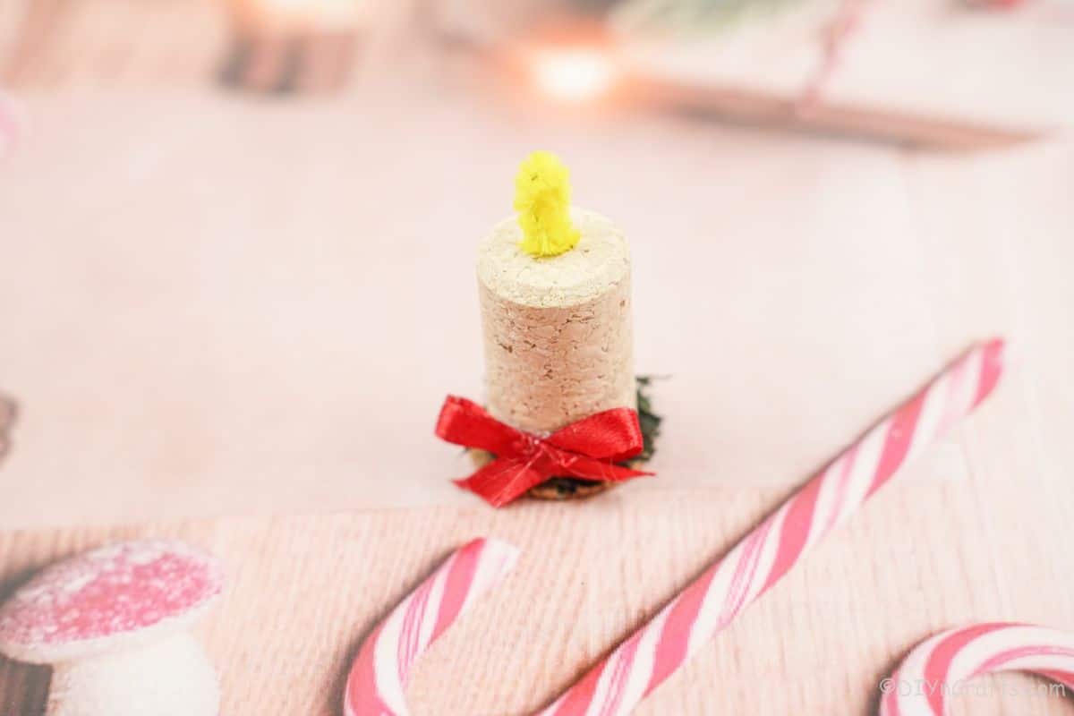 wine cork holiday ornament on pink paper with candy cane
