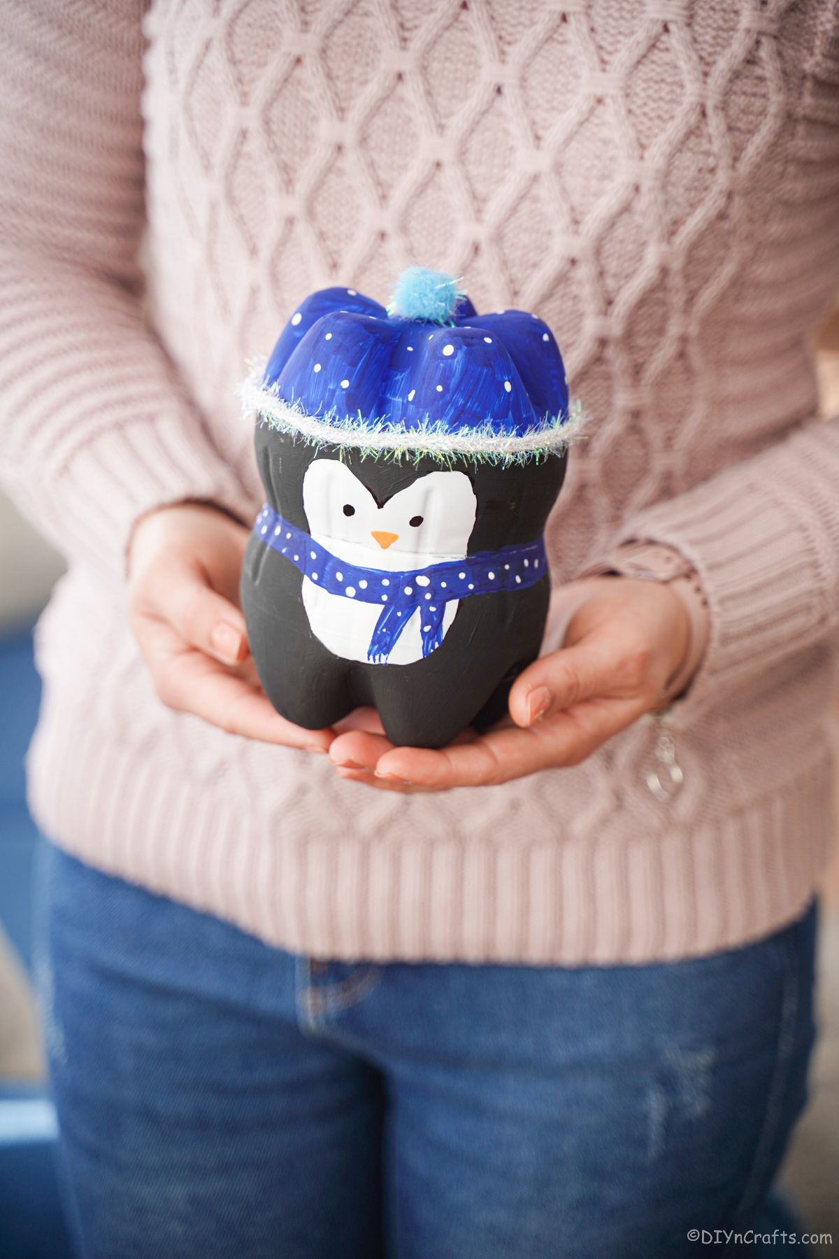 mini bottle penguin with blue hat held in hands