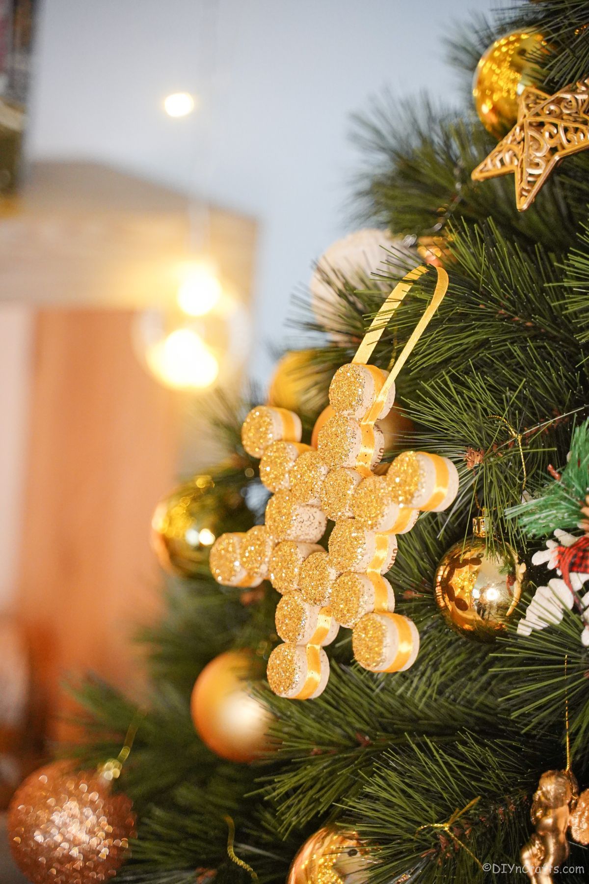 fold glitter snowflake ornament hanging on green christmas tree