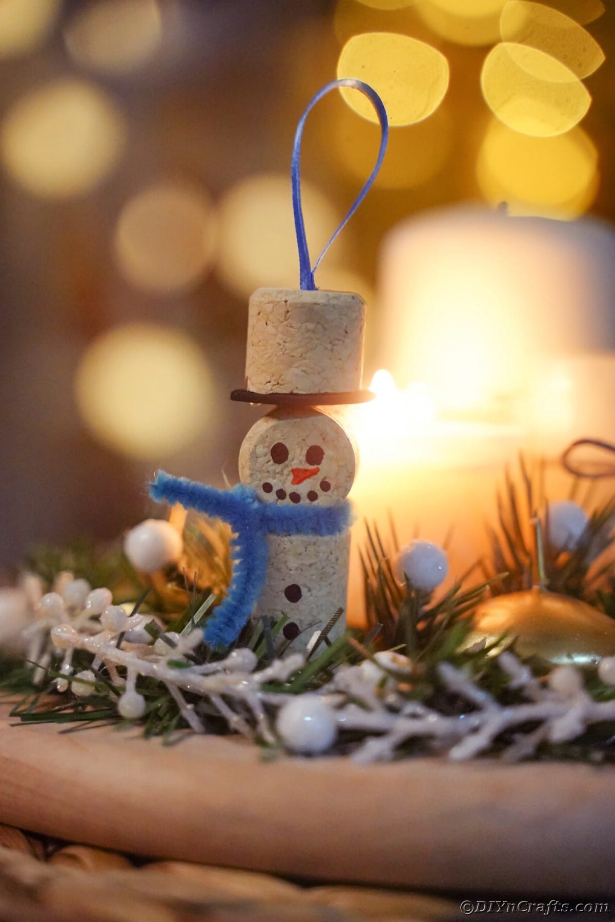 wine cork snowman with blue scarf hanging on tree by white fake berries