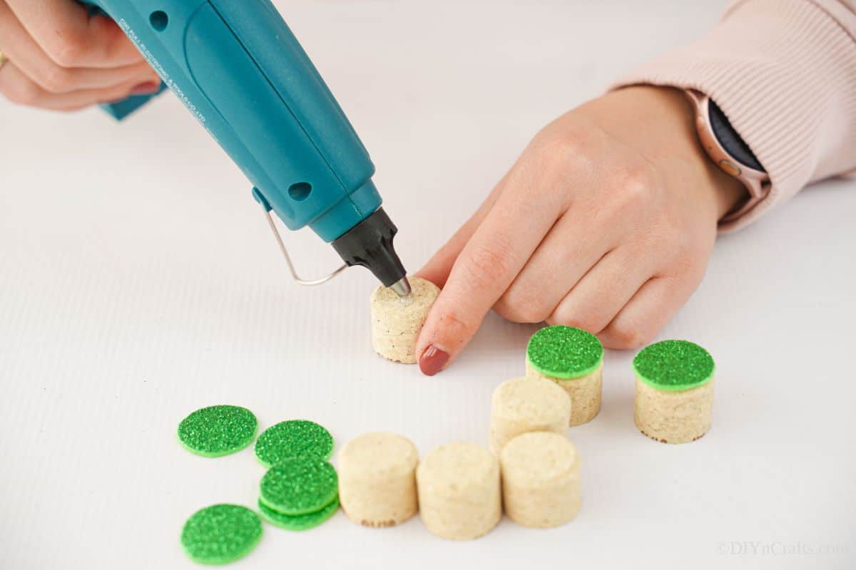 glue gun adding green tops on cork pieces