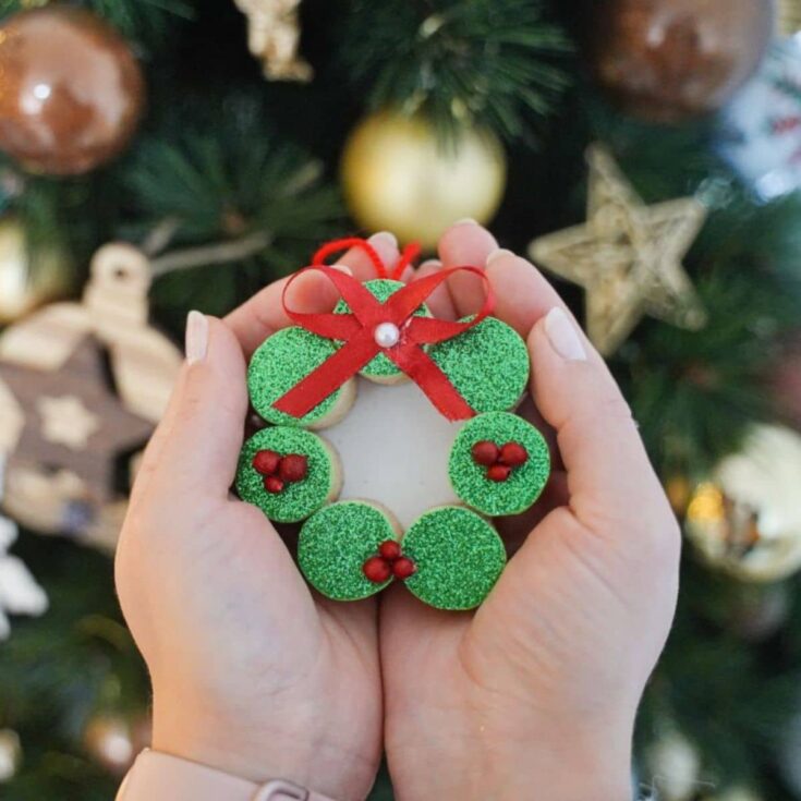 hands holding wine cork ornament by tree