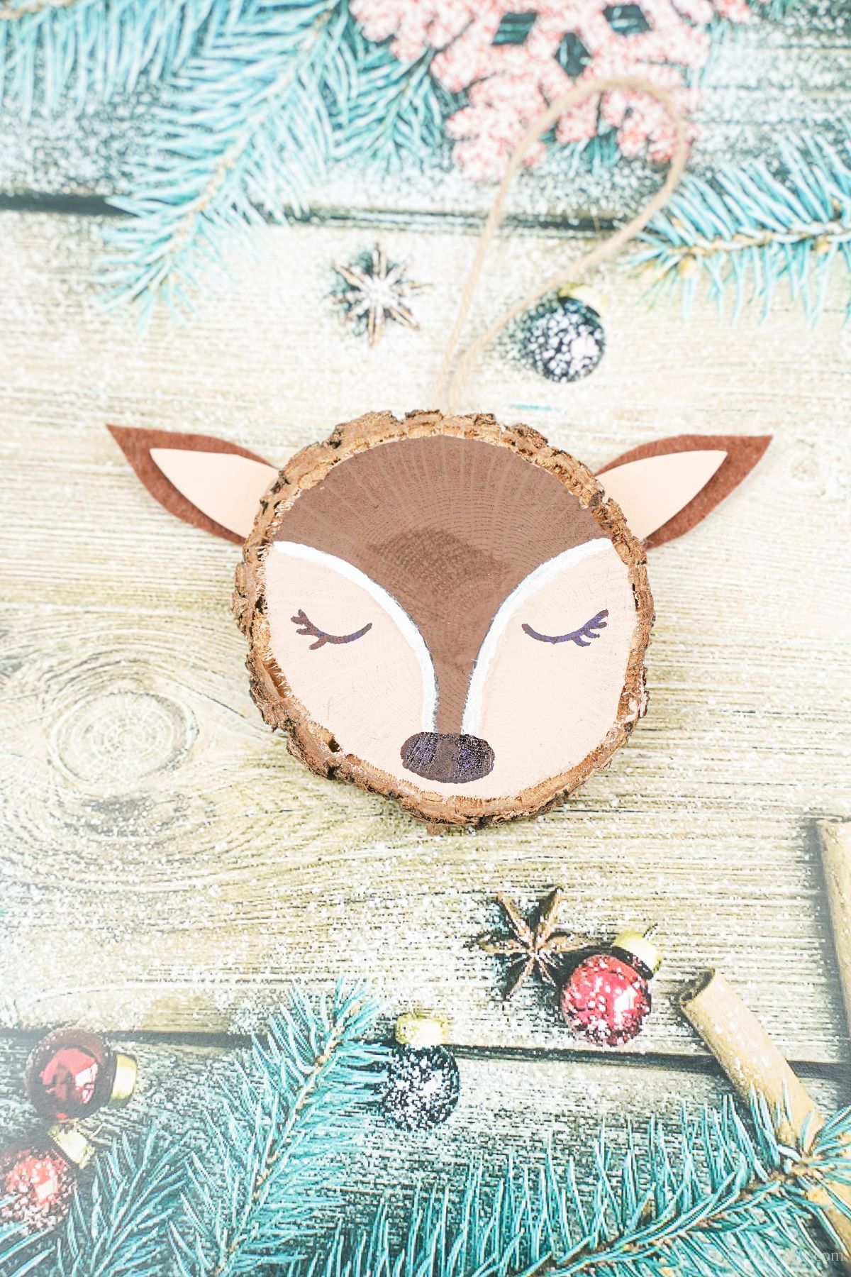 wood slice reindeer with black nose laying on blue holiday paper