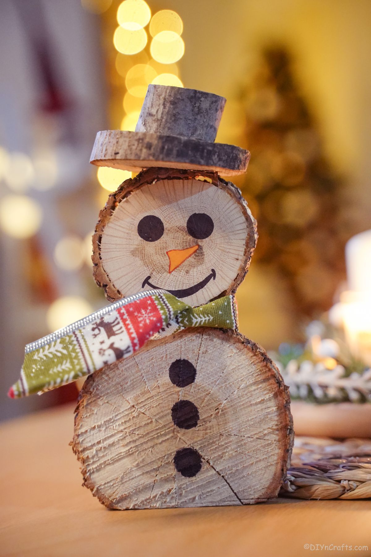 wooden slice snowman on wooden table with green holiday scarf