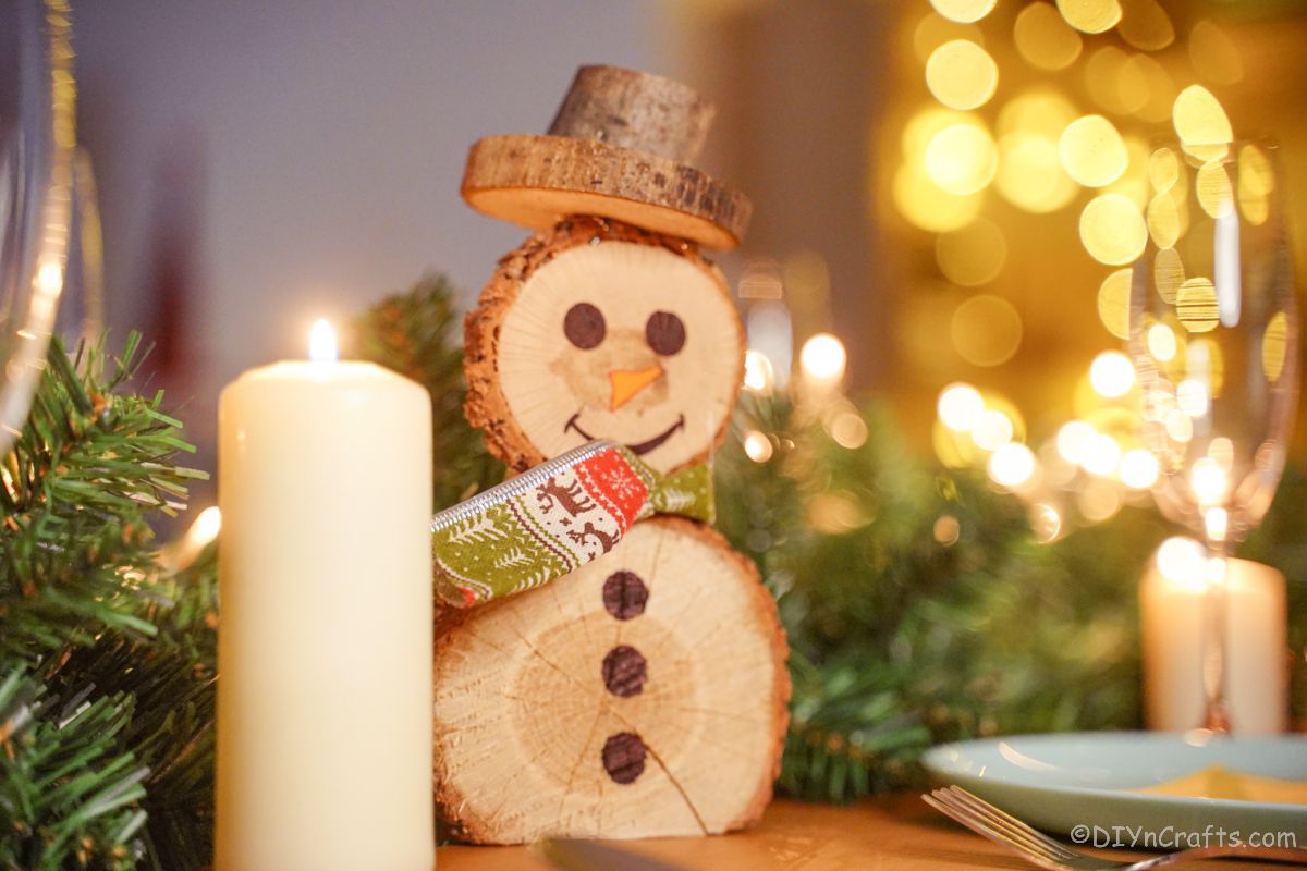 wooden snowman next to greenery and white candle