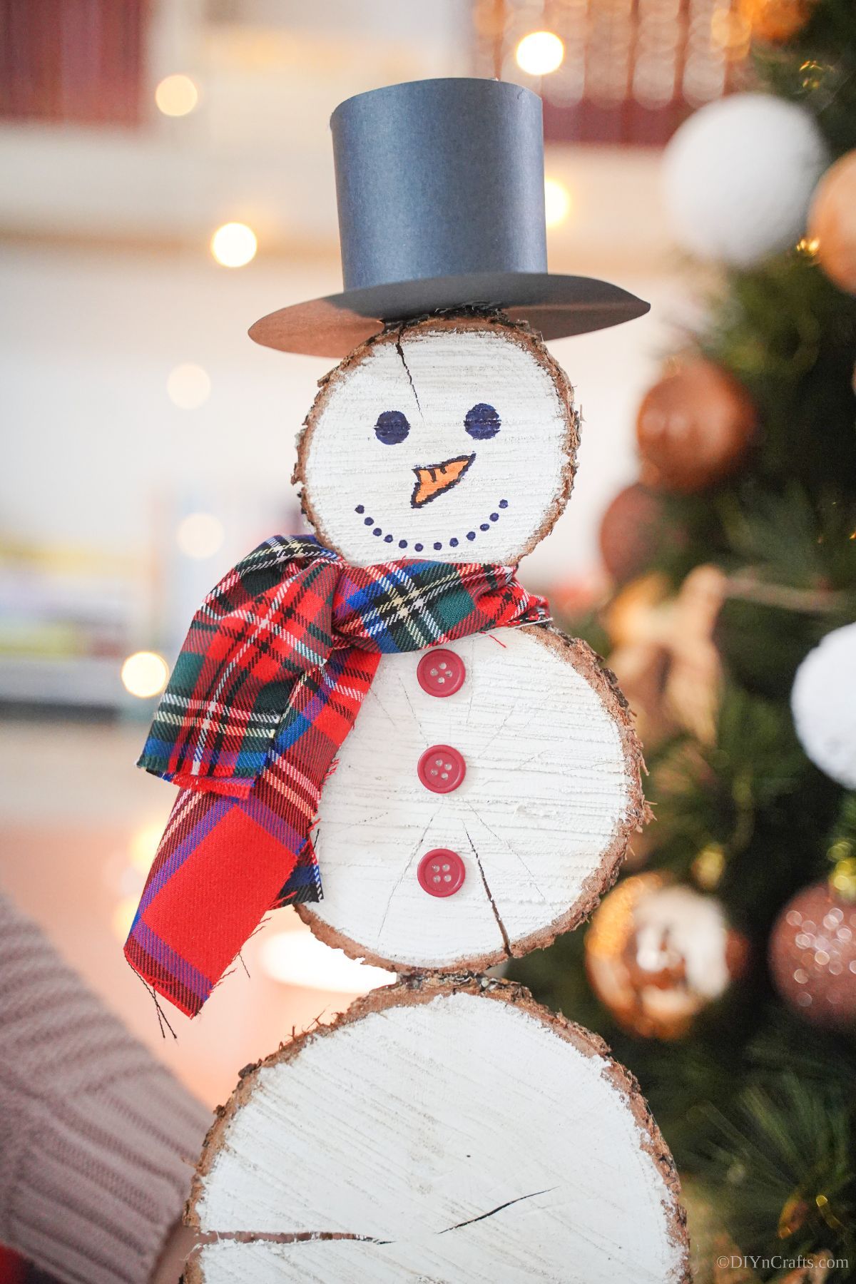 wooden slice snowman in front of holiday tree