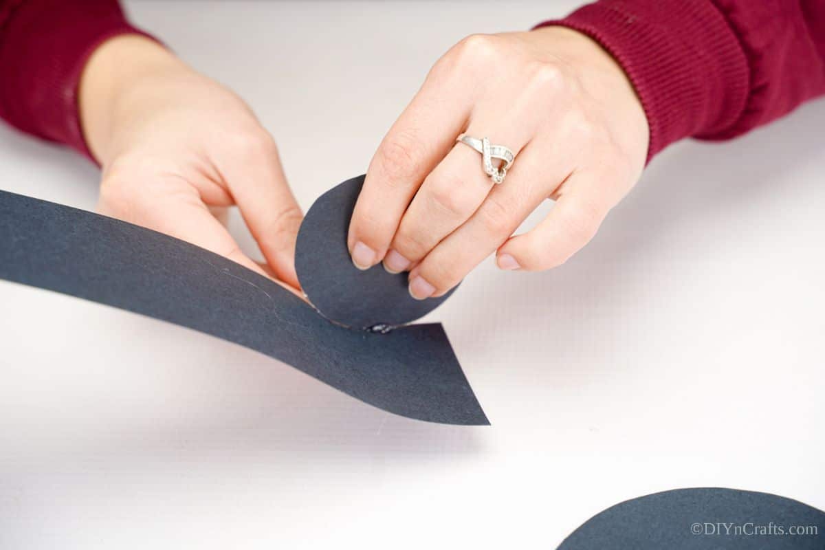 hand rolling black paper around base of paper hat