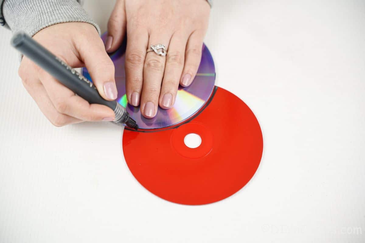 main utilisant un marqueur pour tracer sur un cd peint
