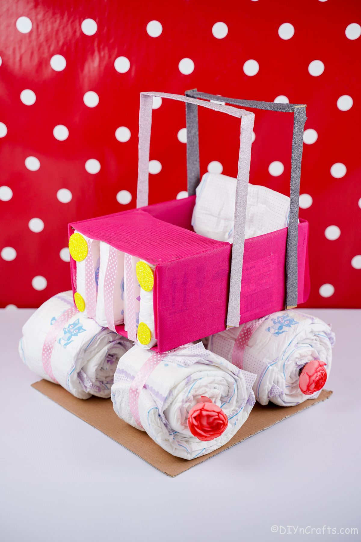 pink safari car diaper cake with red and white polka dot background