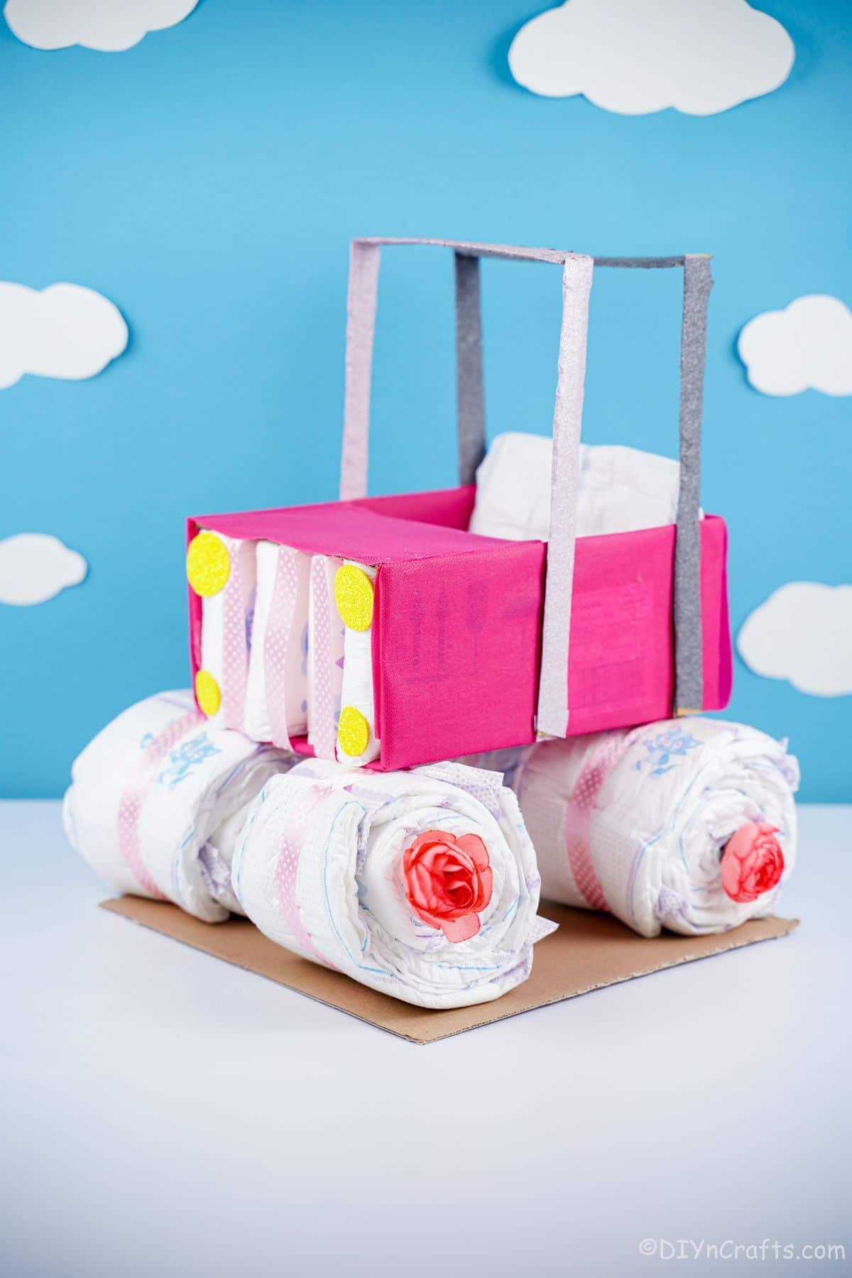 pink safari car diaper cake on white table with blue cloudy background