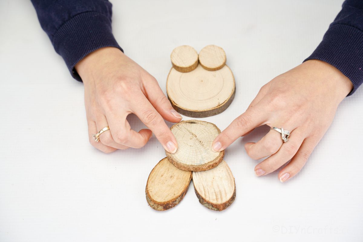hands gluing wood slices together to form bunny head