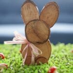 wood slice bunny with pink ribbon around neck on grass