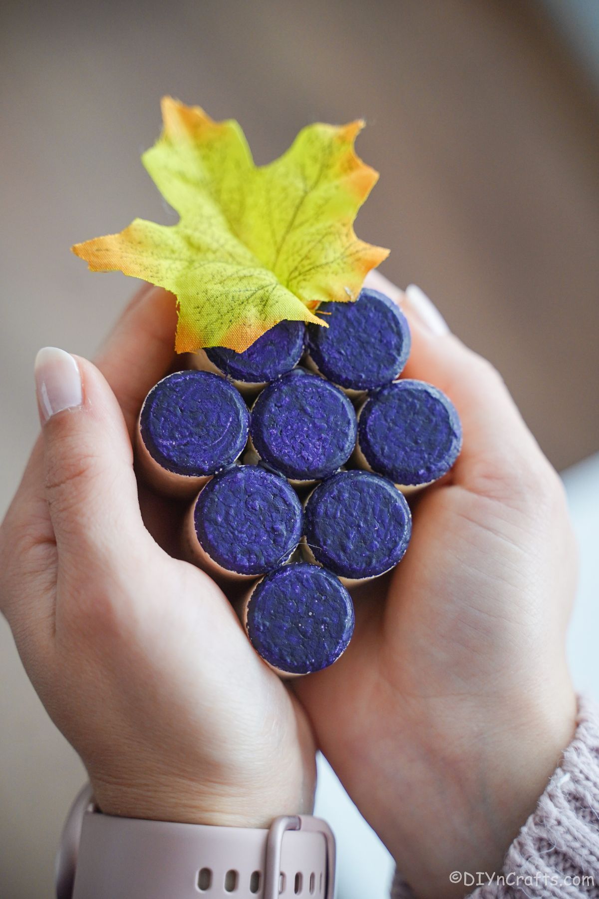 hands holding cork grape cluster painted purple