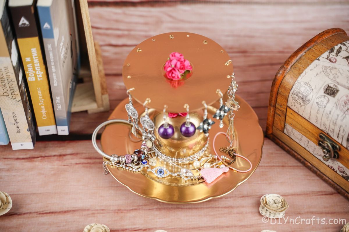 2-tier gold jewelry stand on a wooden table by a small box
