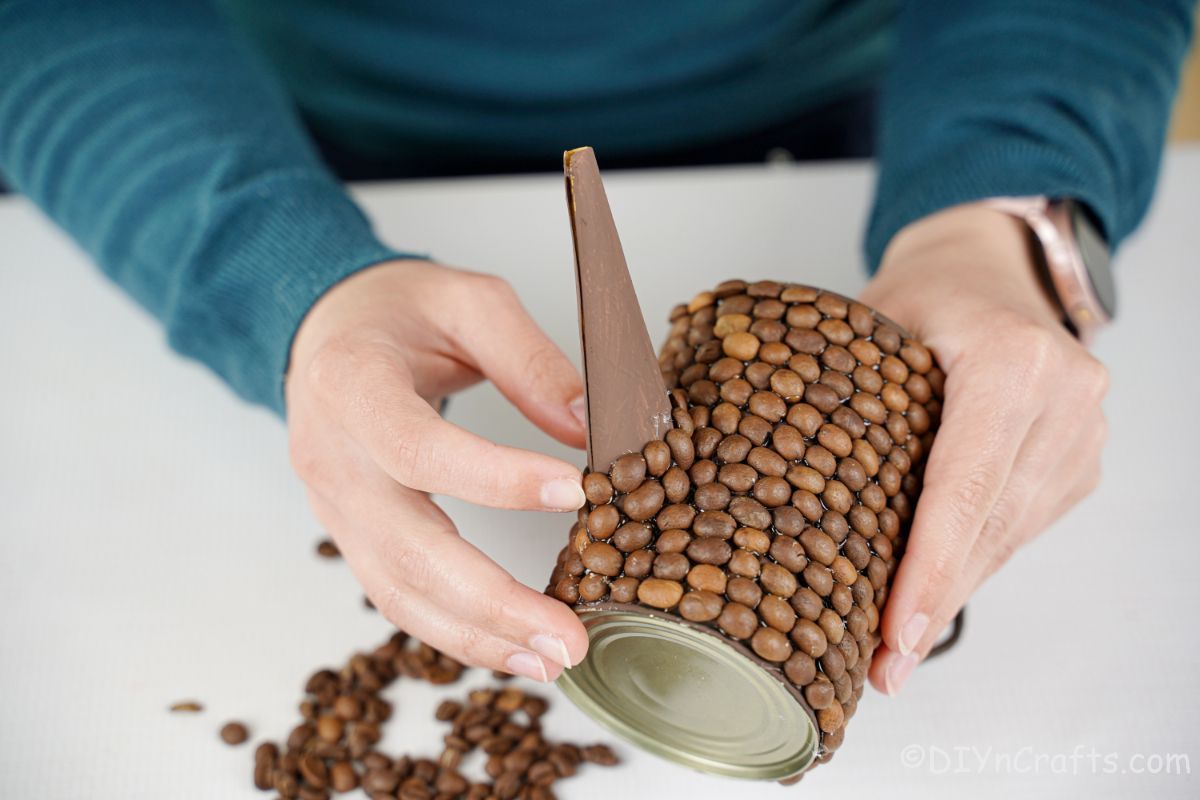 hand gluing coffee beans on spout of watering can