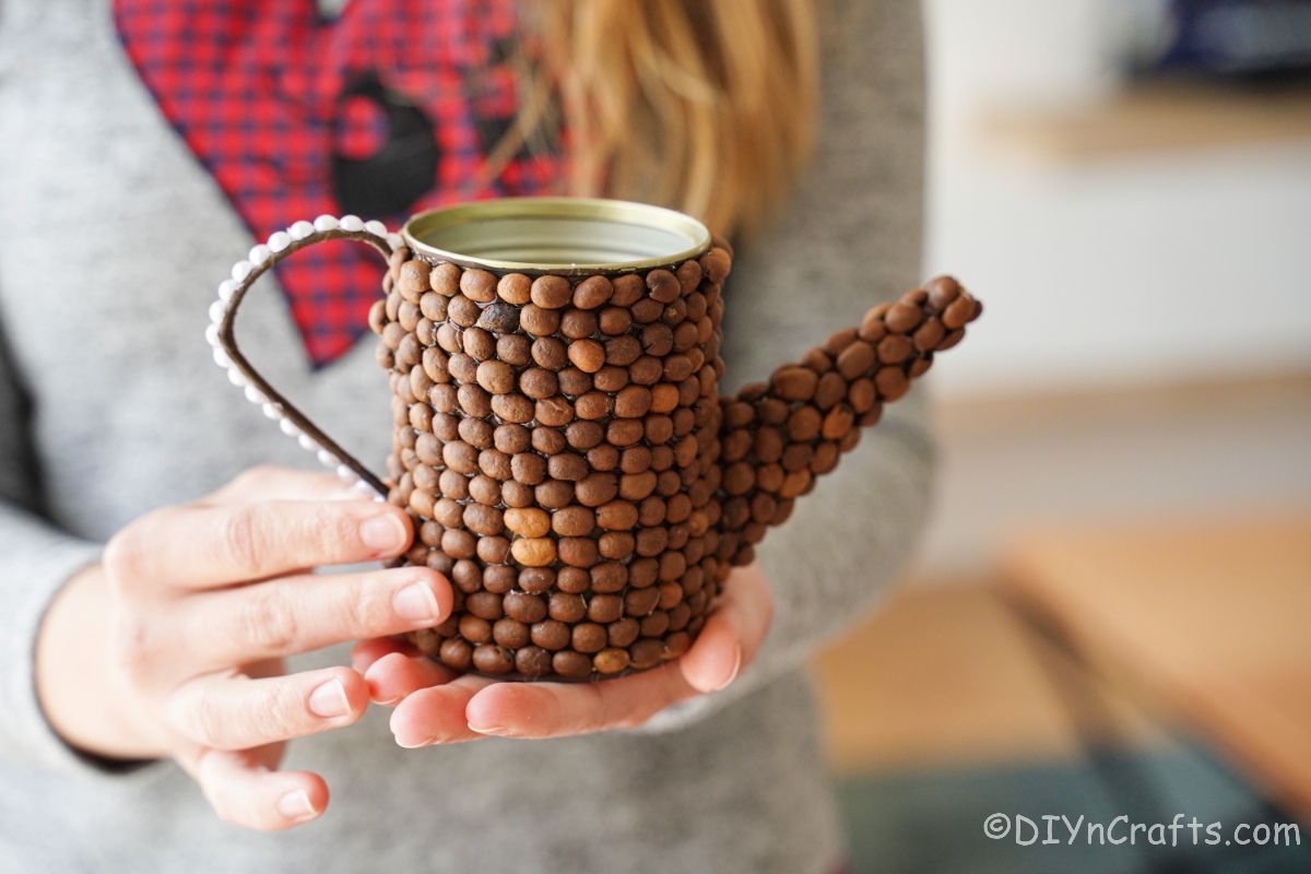 rustic coffee bean covered watering can in ladies hand