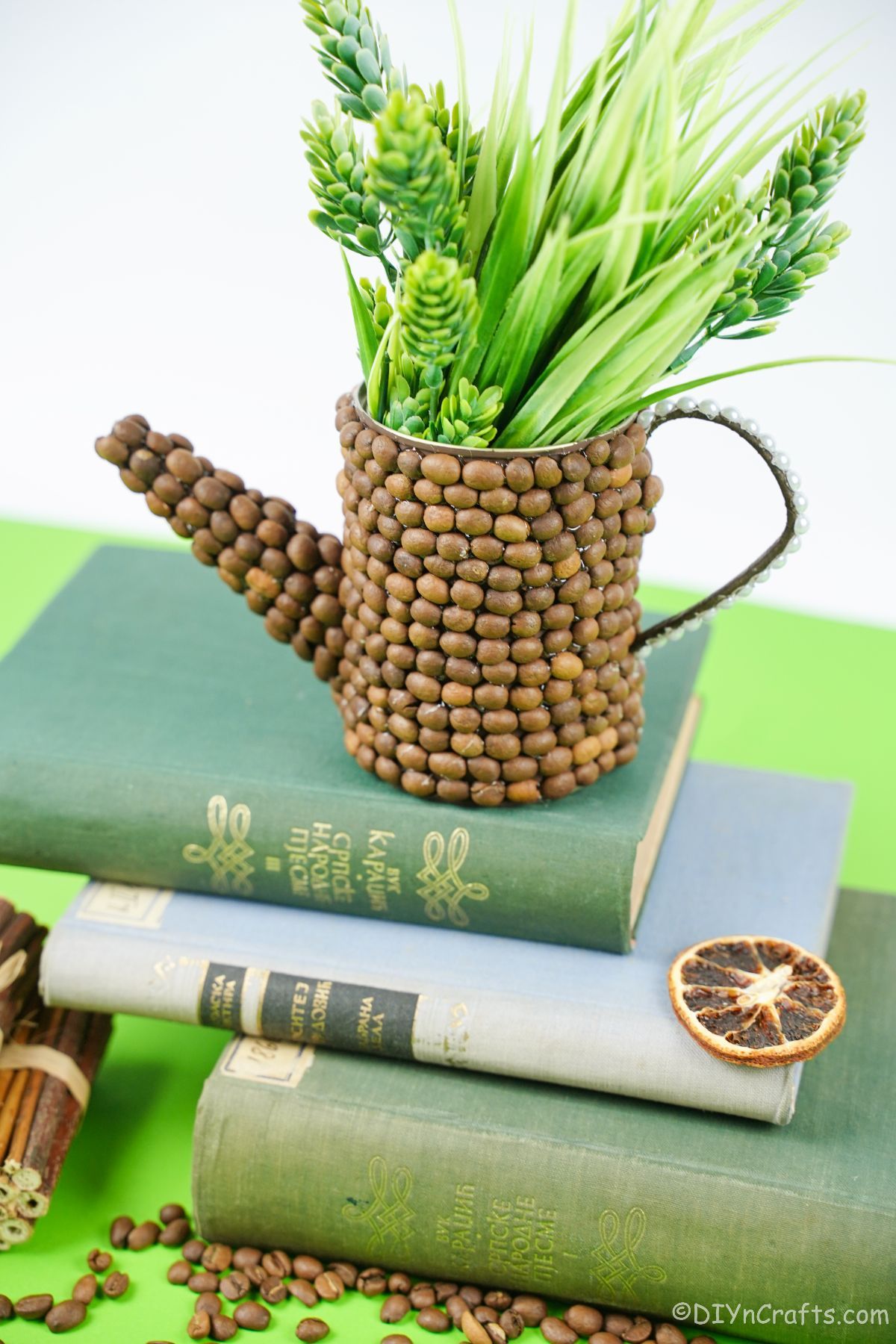 rustic watering can filled with green flowers on stack of books