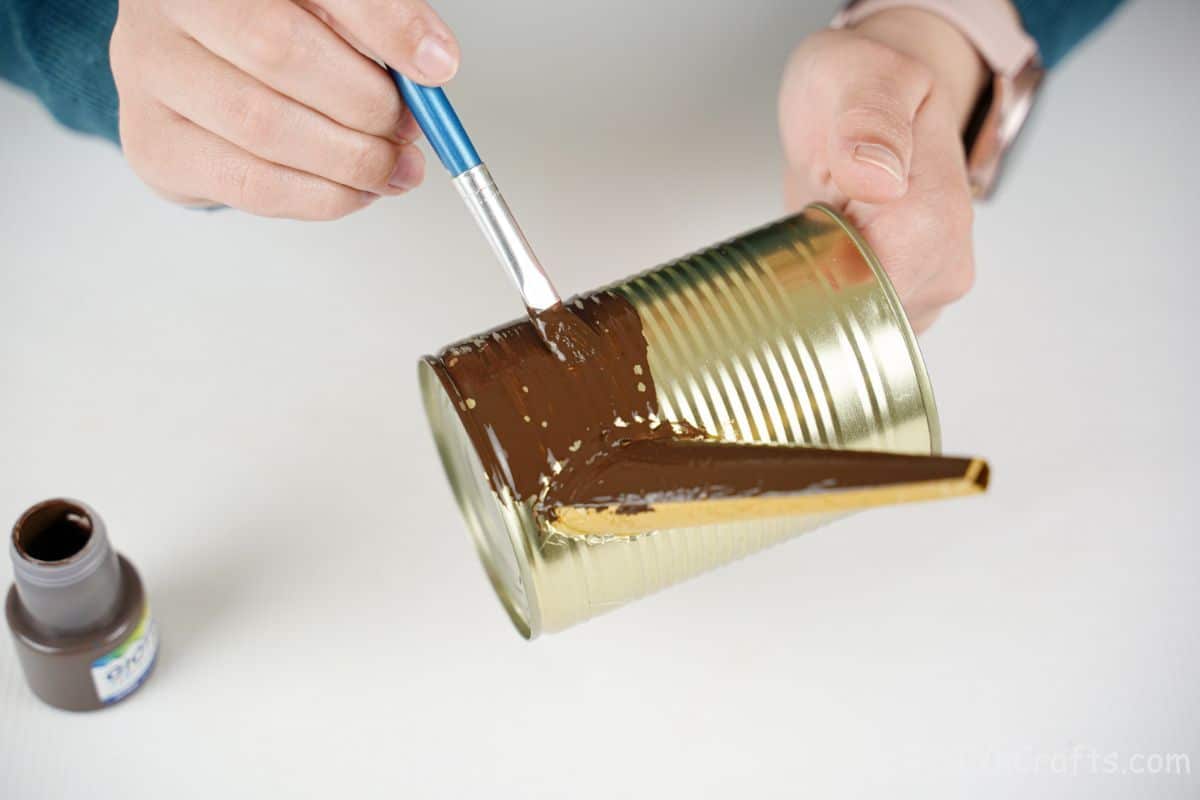 hand painting brown paint onto tin can