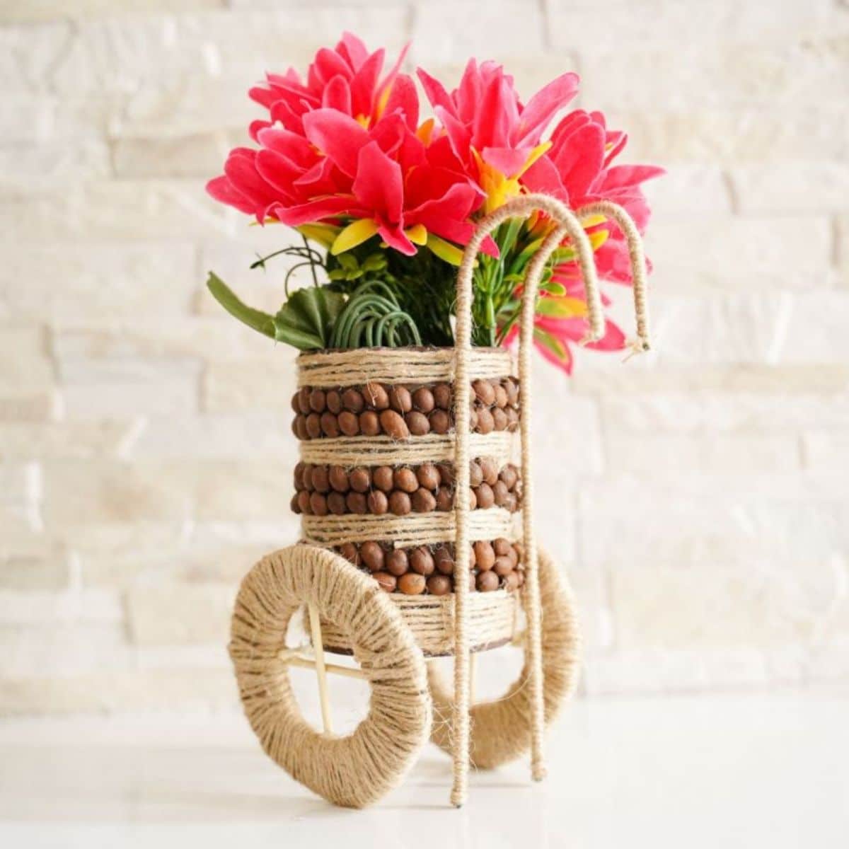 twine and coffee bean can with flowers by brick wall
