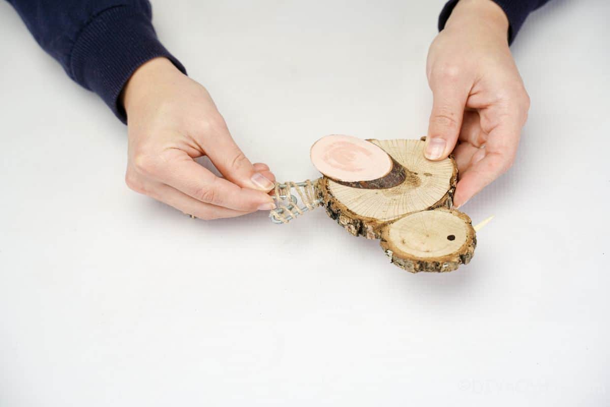 hand gluing tail on wood slice chicken