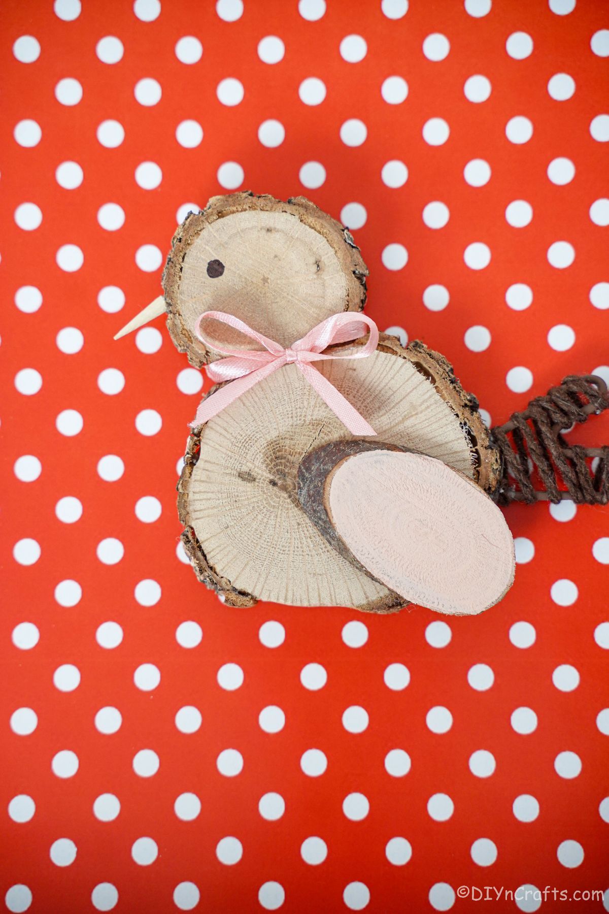 red and white polka dot paper underneath wood slice chick