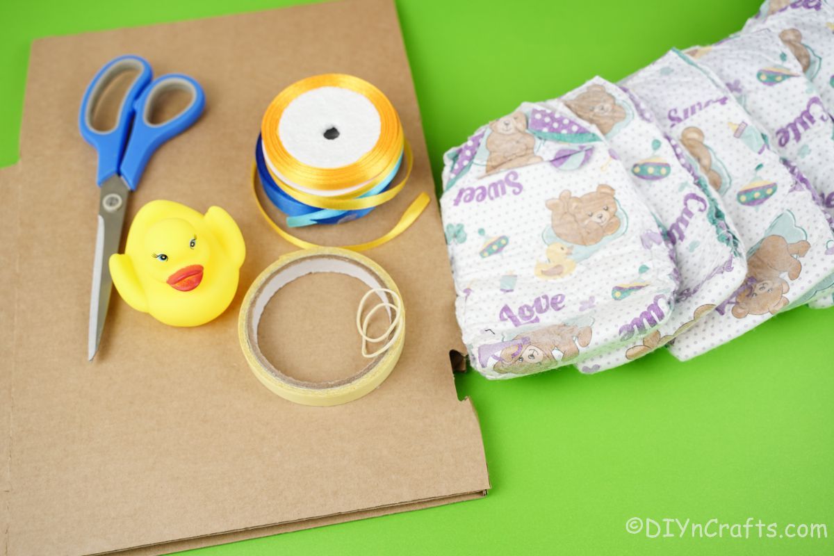 diapers cardboard ribbon and scissors on green table
