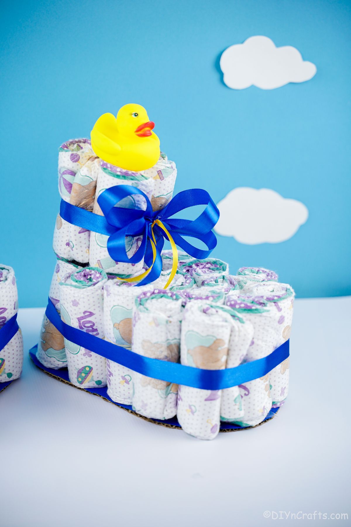 rubber ducky on top of baby bootie diaper cake with blue wall in background