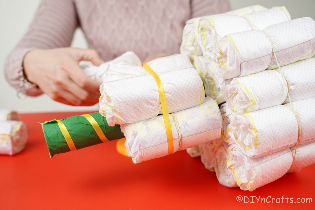 hand stuffing diapers into row around green cardboard tube