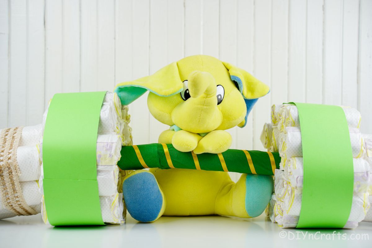 green barbell diaper cake with mini elephant in front of white wall