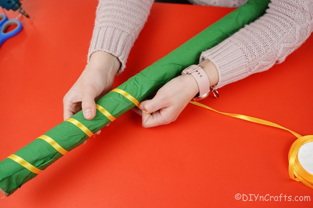 wrapping yellow ribbon around green tube