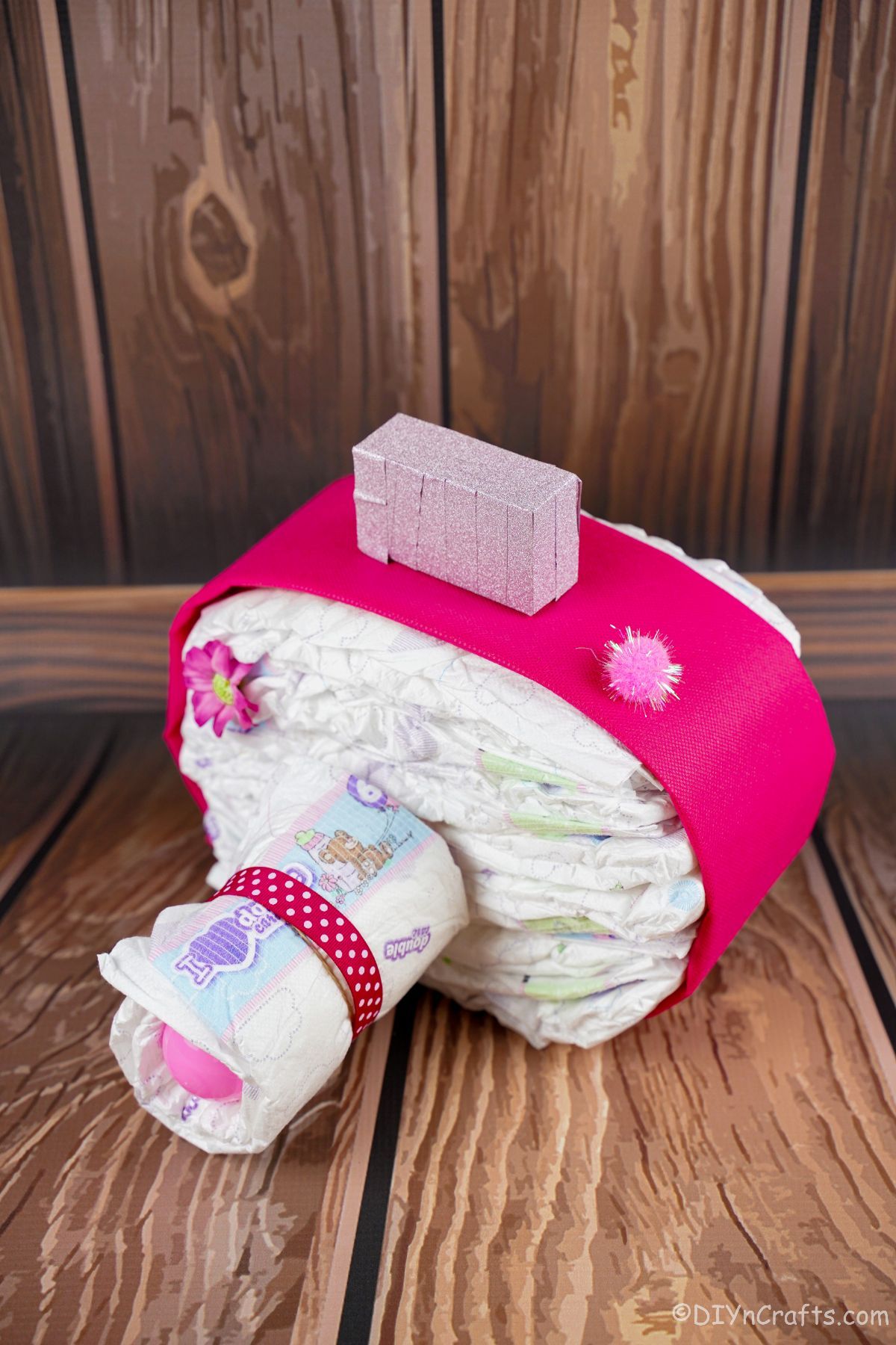 pink diaper cake camera with wood paneling behind it