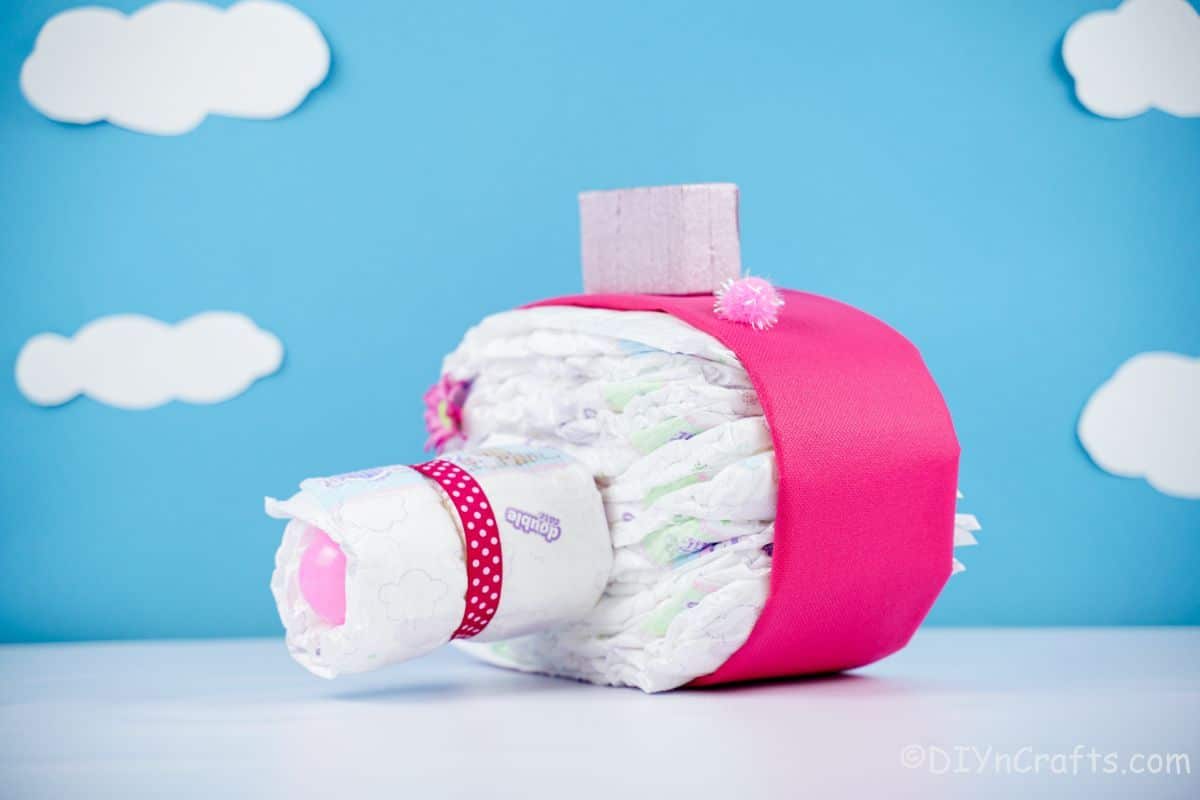 pink accents on diaper cake camera with blue background