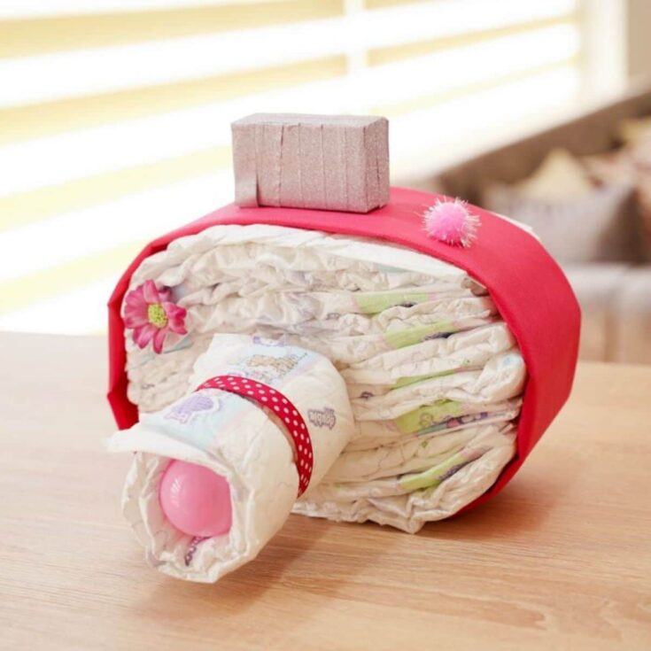 pink camera diaper cake on light wood table