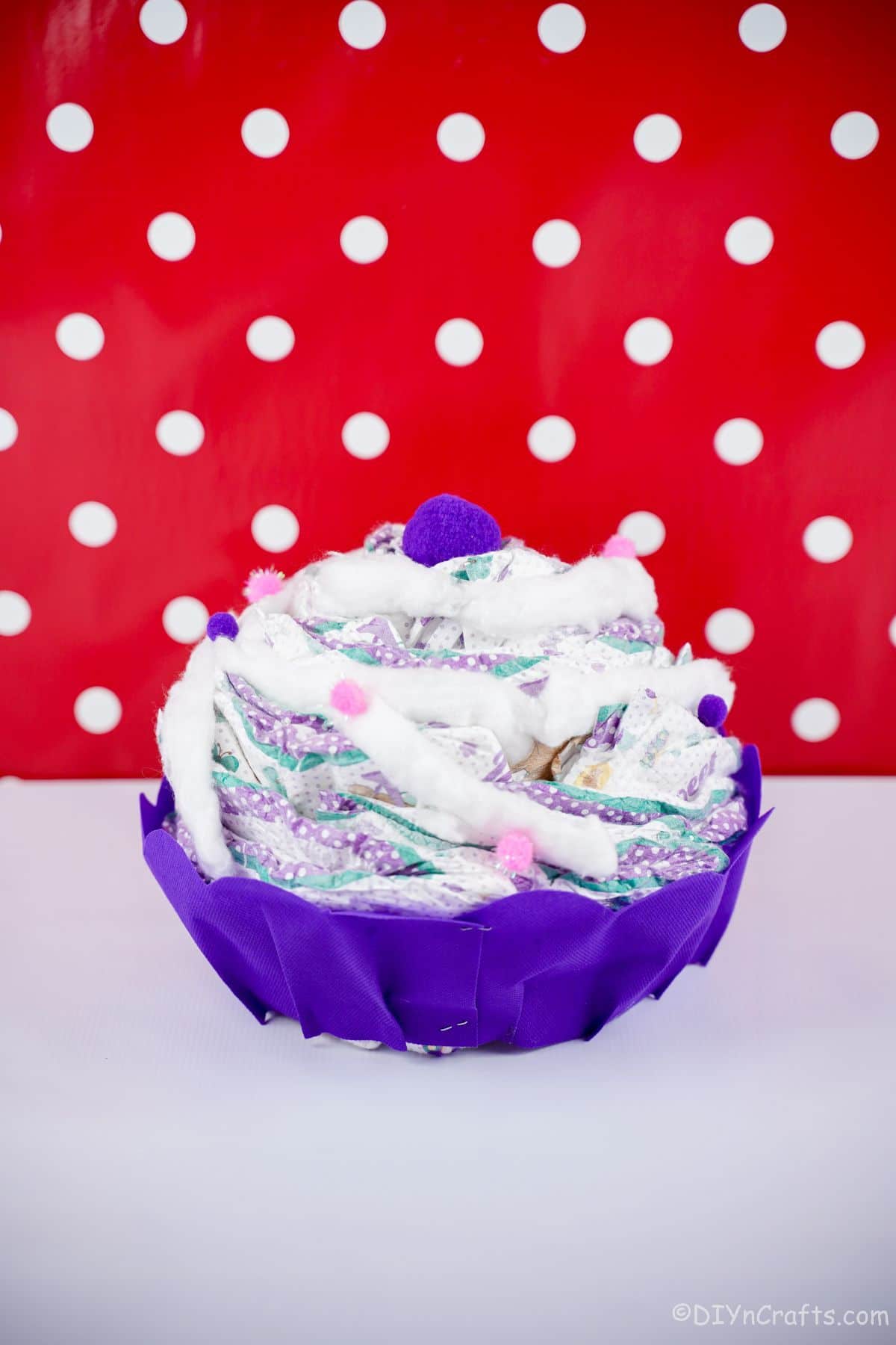 diaper cake with purple accents in front of red and white polka dot wall