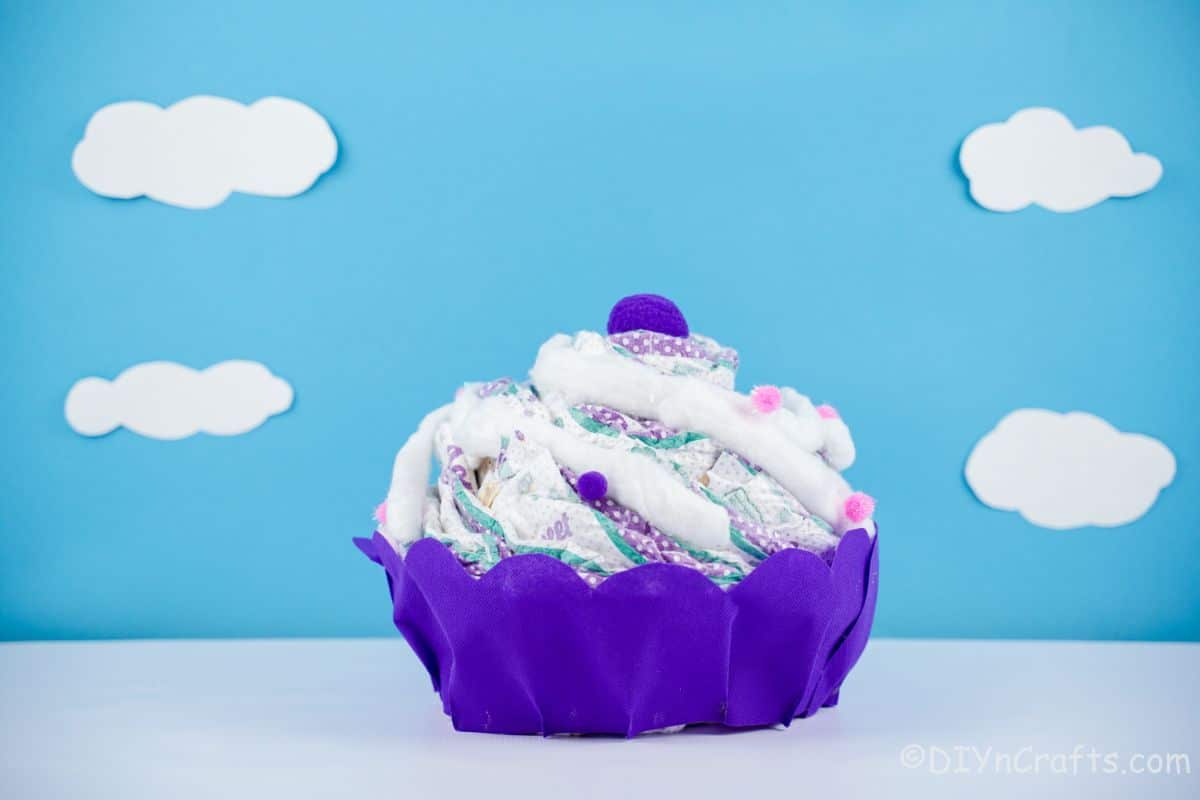 purple cupcake diaper cake in front of blue background with white clouds