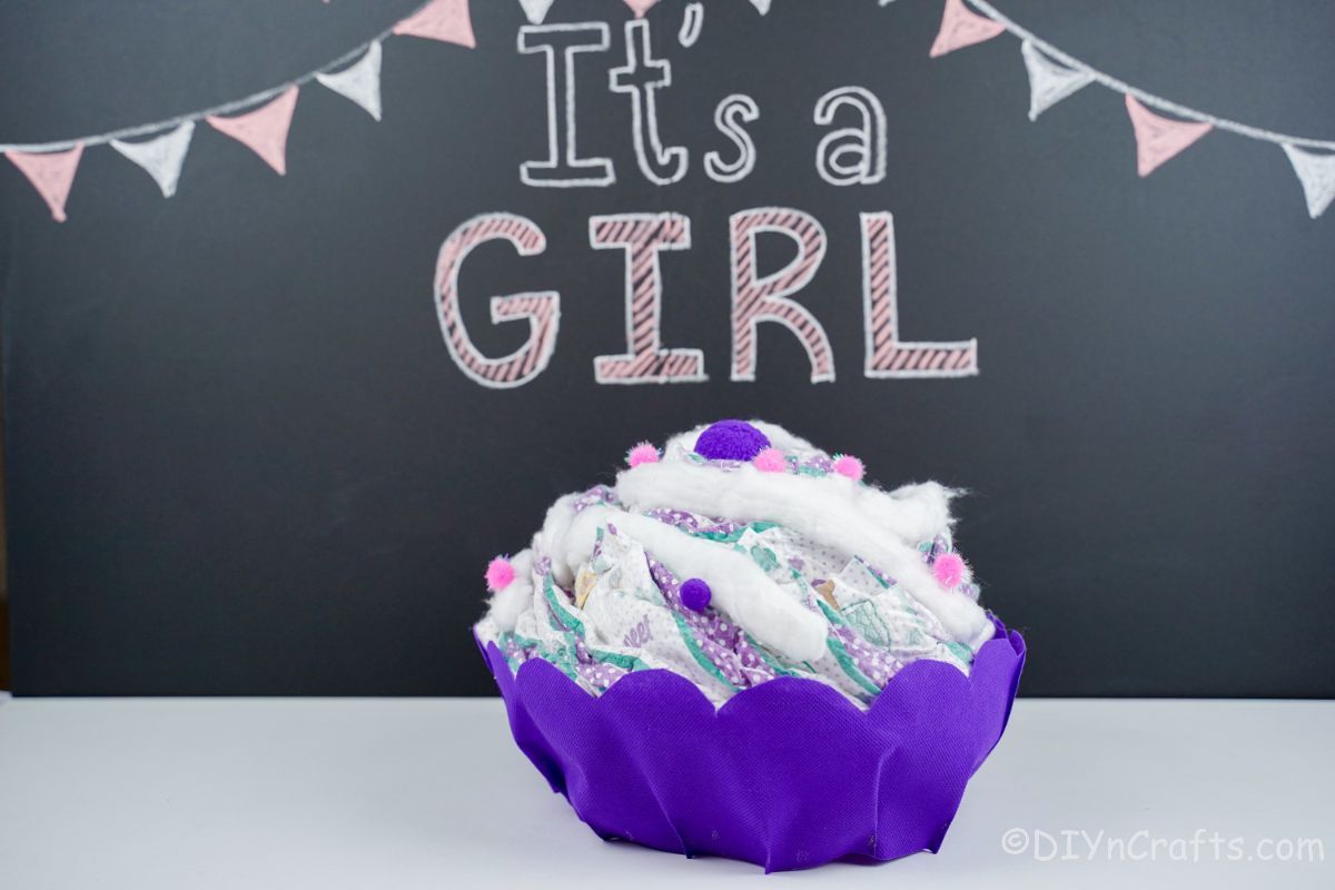 purple cupcake diaper cake in front of chalkboard wall